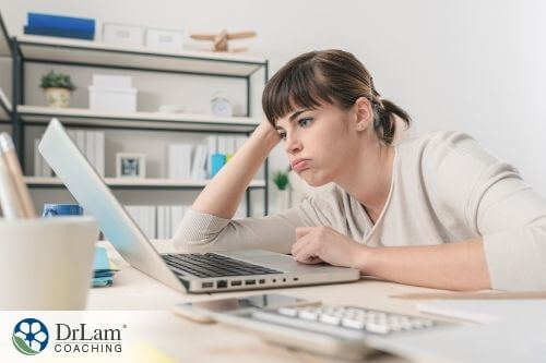 An image of a woman who looks tired while looking at her computer