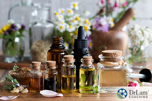 group of bottles of essential oil with herbs and flowers on the table