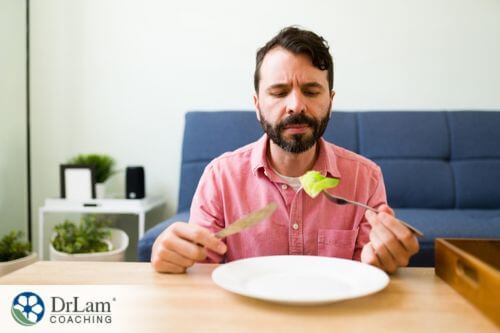 An image of a man looking at a lettuce leaf on his fork