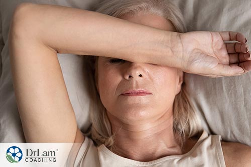 An image of a fatigued woman laying with one arm over her face