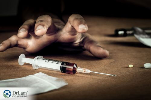 An image of someone reaching across the floor towards a syringe