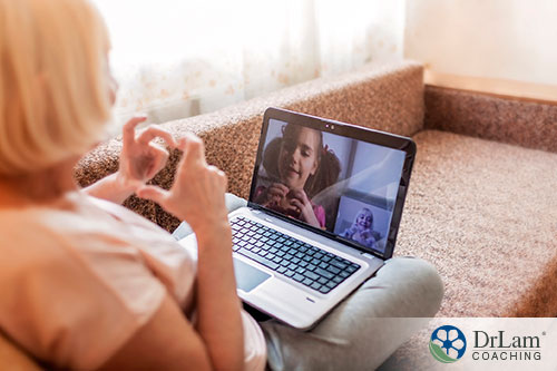An image of an old woman video chatting with a child making heart shapes with their hands