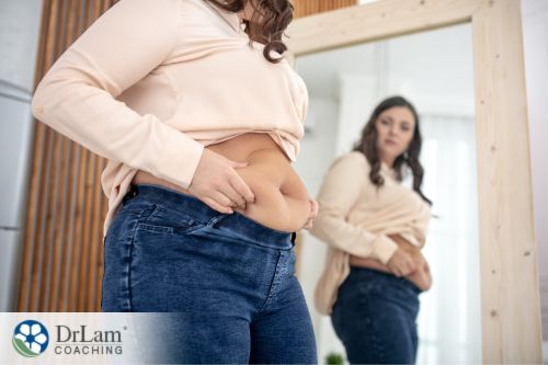An image of a woman looking at her belly in the mirror