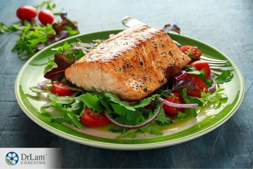 An image of salmon on a plate of salad