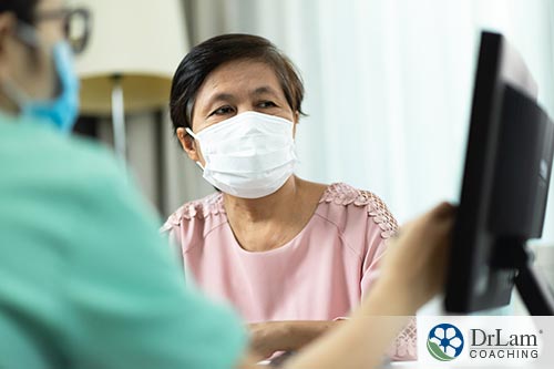 An image of a woman wearing a mask and her doctor showing her something on a screen
