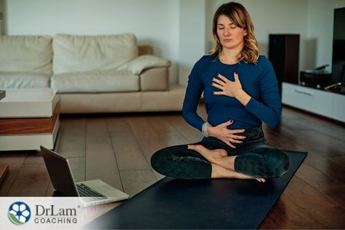 An image of a woman sitting on a yoga mat as she meditates