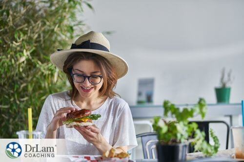 An image of a woman eating a sandwitch as she smiles
