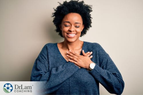 An image of a woman holding her hands on her chest as she smiles