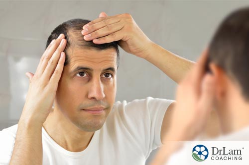 An image of a man looking in the mirror at a balding spot on his head while contemplating if possible Post Finasteride Syndrome is worth the risk to regrow his hair
