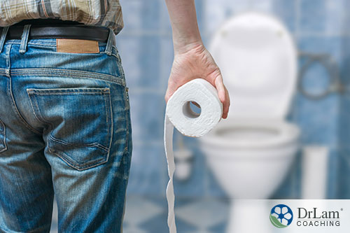 An image of a man holding a roll of toilet paper heading to the toilet