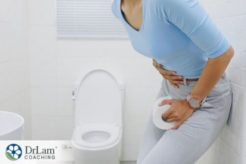 An image of a woman holding her stomach at the toilet