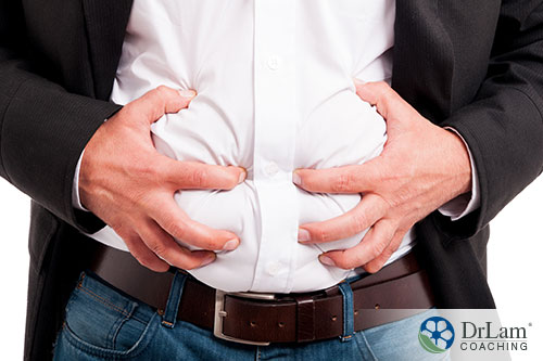 An image of a man holding his bloated stomach