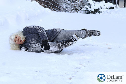 An image of a old woman falling in the snow holding her knee