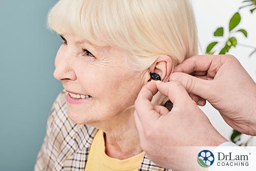 An image of an older woman being fitted for hearing aids