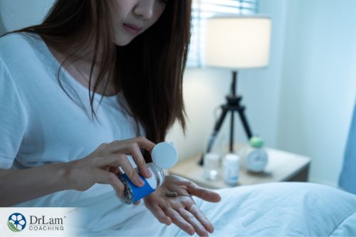 An image of a woman getting a pill out of the bottle while she sits in bed
