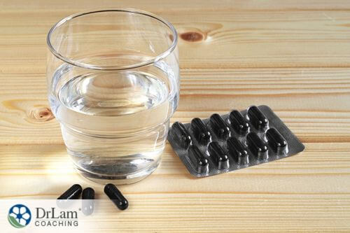 An image of activated charcoal capsules and a glass of water