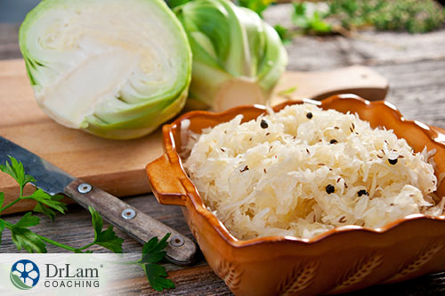 An image of sauerkraut in a brown bowel with raw cabbage in the background