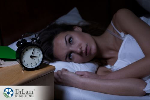 An image of a lying woman looking at the alarm clock