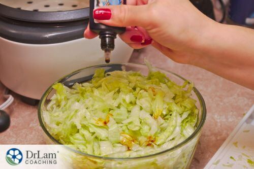 An image of a woman adding drops of silver to a bowl of salad
