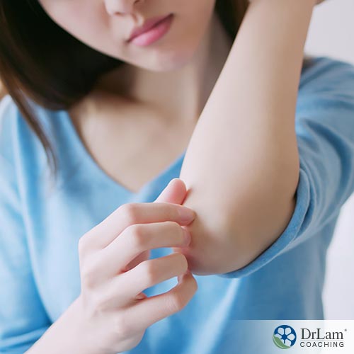 An image of a woman looking at and feeling her elbow