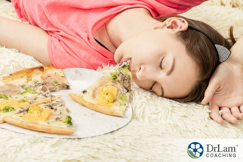 An image of a woman asleep with pizza by her face