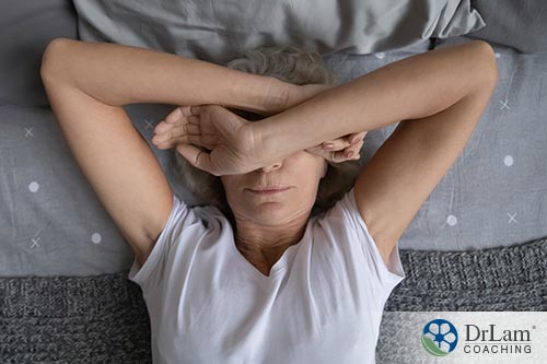 An image of an older woman laying in bed with her hands crossed over her eyes