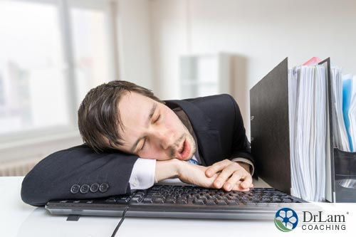 An image of a man asleep on his keybord in a suit, needing some sleep problem solutions for his fatigue and reduced productivity