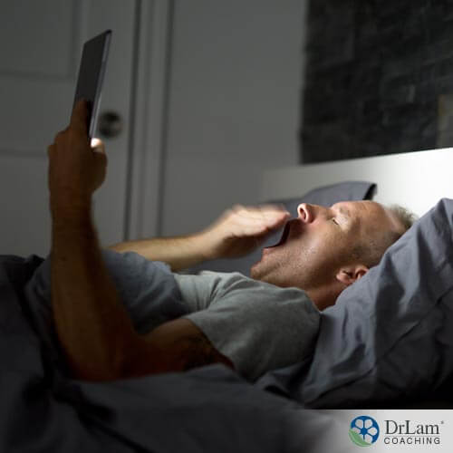 An image of an older man in bed with an electronic, which is one thing needing to be eliminated according to these sleep problem solutions