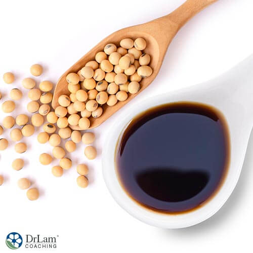 An image of soy sauce in a spoon and dried soy beans