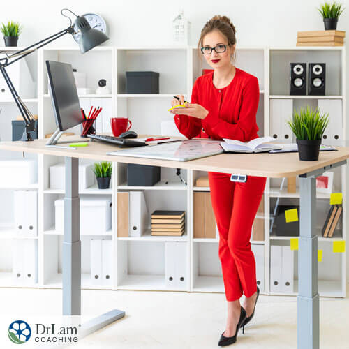 An image of a woman in a red suit standing at her desk working