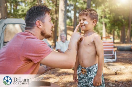 An image of a man applying sunscreen on his son