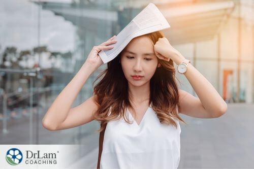An image of a stressed woman covering her head with a newspaper