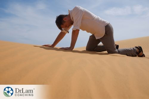 An image of a man crawling in the desert sand