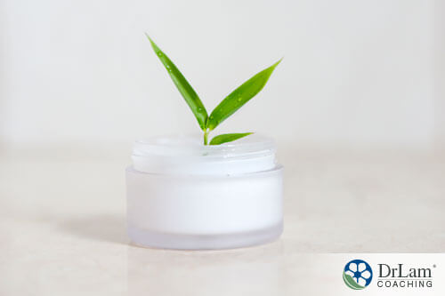 An image of a small container of sunscreen with a blade of grass in it