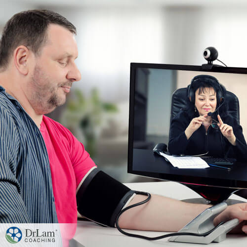 An image of an middle age man taking his blood pressure while on a telehealth appointment