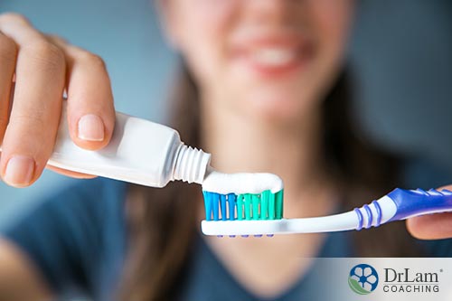 An image of a woman putting toothpaste on her toothbrush