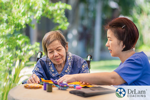 An image of a young nurse helping an old woman in a wheelchair with crafts at a table