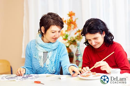 An image of a woman doing painting crafts with another woman who is autistic 