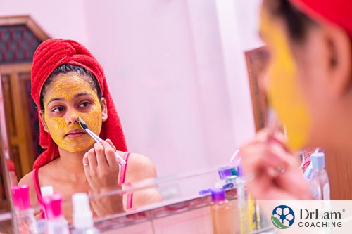 An image of a young woman spreading turmeric on her face