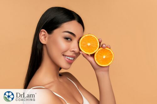 An image of a woman holding up a sliced orange