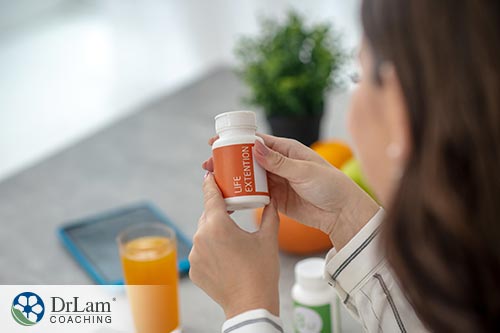 An image of a woman looking at a vitamin bottle