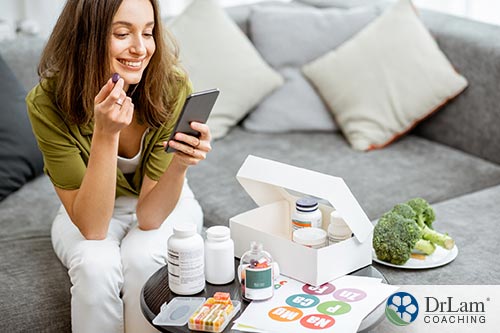 An image of a woman taking her vitamins while looking on her phone
