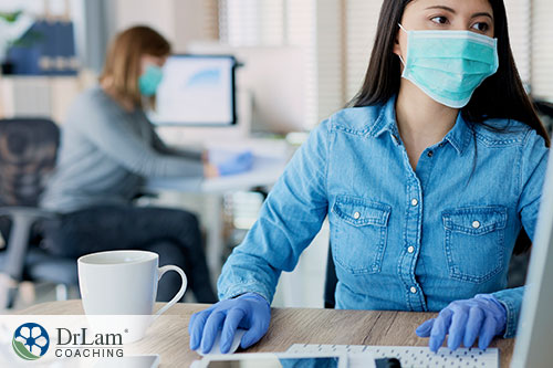 An image of a young woman wearing protective gear at her computer desk